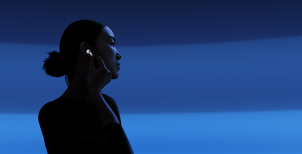 Una persona sostiene la parte inferior de uno de sus AirPods 5 con el pulgar y el dedo índice para cambiar entre modos de audio