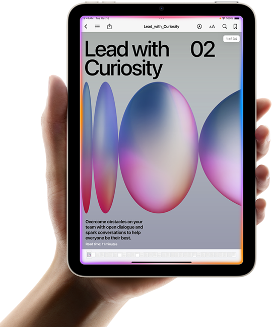 Un usuario sostiene un iPad mini en posición horizontal con una mano. La pantalla muestra la app Libros