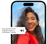 Un iPhone&nbsp;15 muestra cómo la funcionalidad VoiceOver lee la descripción de una imagen: una persona con pelo negro ondulado sonriendo