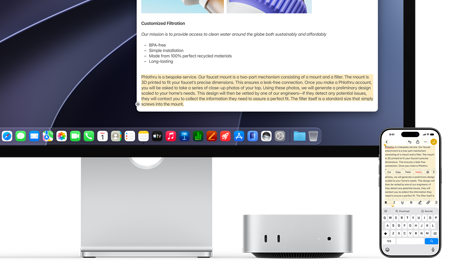 Parte frontal de una Mac mini, ubicada debajo de un monitor Studio Display, hay un iPhone a la derecha del dispositivo y la pantalla, con texto seleccionado y comandos de cortar, copiar, pegar y Autorrelleno en la parte superior que corresponden al texto resaltado en pantalla, que muestra el Portapapeles Universal
