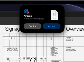 Una pantalla muestra la Dynamic Island con una solicitud de AirDrop en una ventana pequeña sobre un archivo de Adobe Acrobat abierto