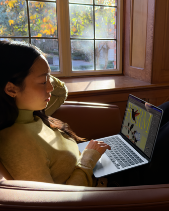 Una persona sentada en una silla usa una MacBook Air