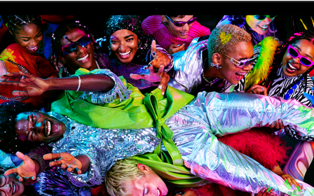 Imagen colorida de una persona en posición horizontal siendo sostenida por una multitud en una fiesta, destacando la brillante pantalla Liquid Retina XDR de la MacBook Pro