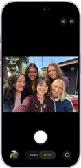 iPhone 17, frente, la pantalla muestra la cámara frontal Center Stage abierta con una selfie grupal de cinco personas centradas en el encuadre