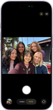 iPhone 17, frente, la pantalla muestra la cámara frontal Center Stage abierta con una selfie grupal de cinco personas centradas en el encuadre